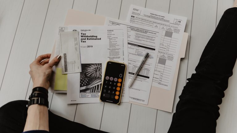 Person reviewing finances with a calculator and paperwork, illustrating buying a home with student loans in Texas