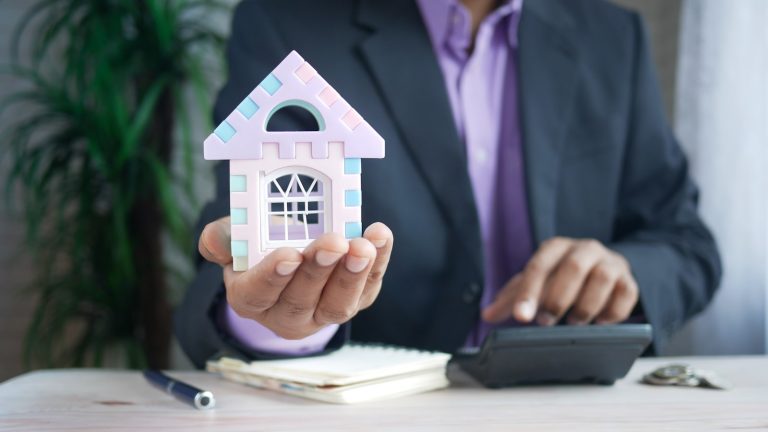 Buyer calculating a down payment in Texas with a model house and calculator