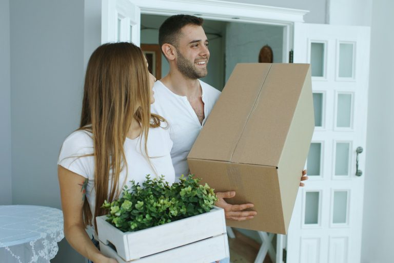 Couple carrying moving boxes into a new Texas home after a job change and relocation