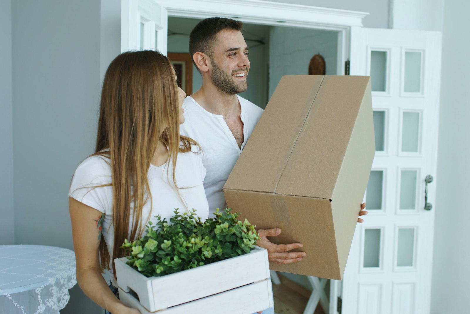 Couple carrying moving boxes into a new Texas home after a job change and relocation